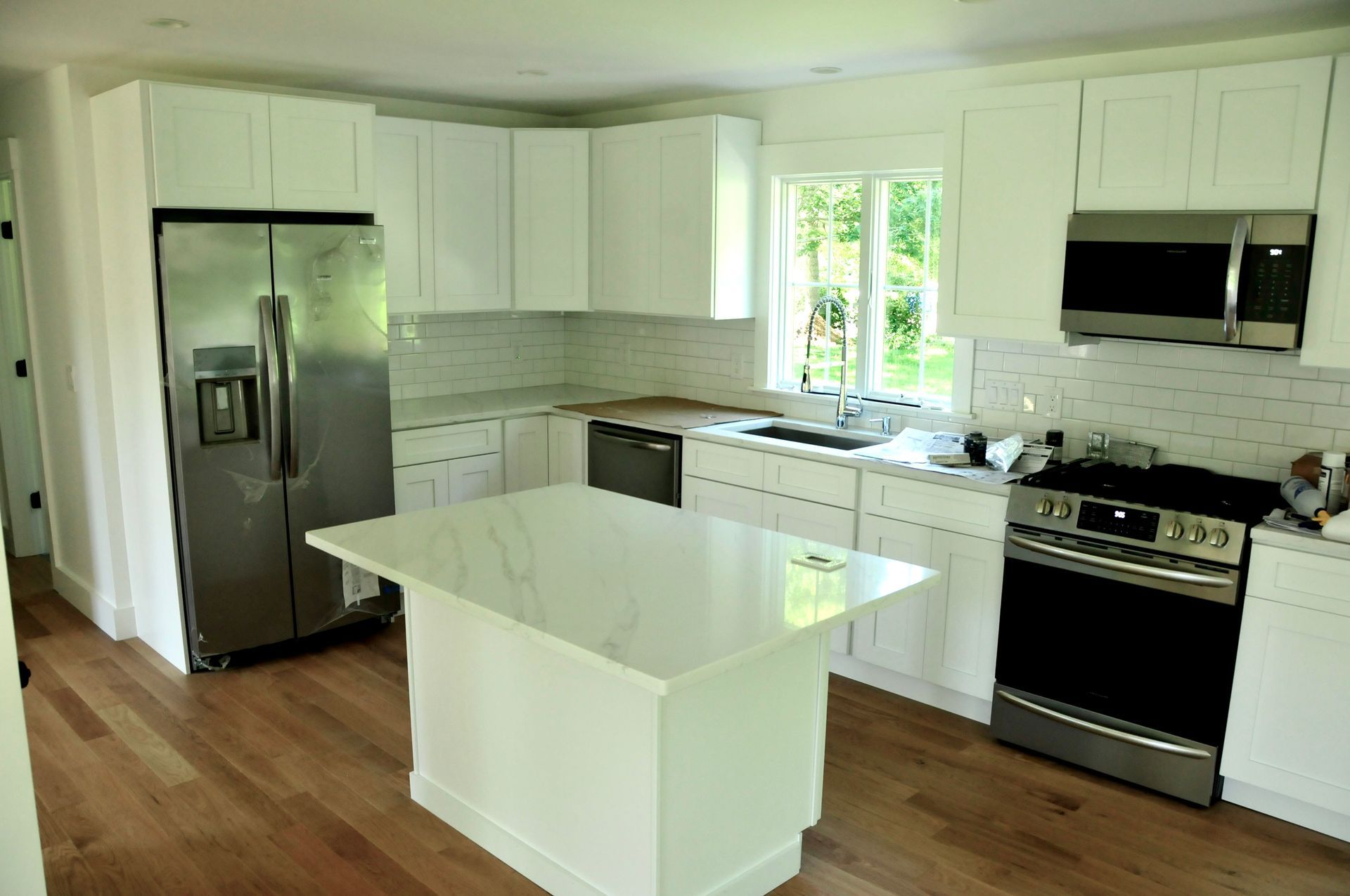 Finished kitchen remodel with white shaker cabinets, subway tile backsplash, and stainless appliances